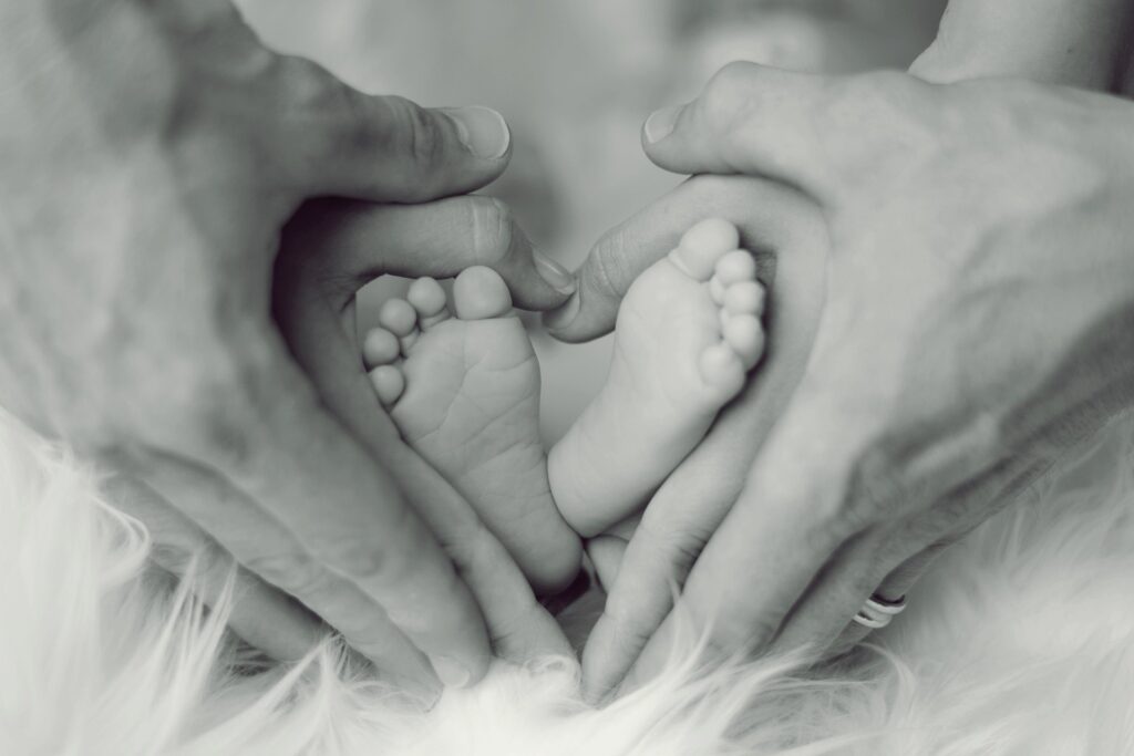 future family aspirations - baby feet and two sets of adults hands making a heart